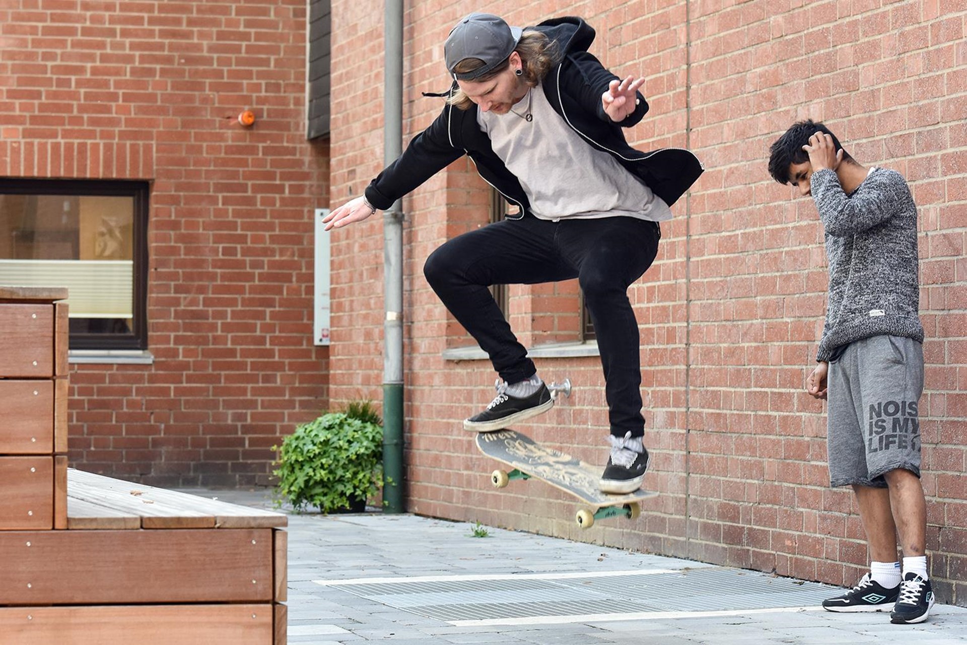 Zwei Jugendliche auf Platz mit Skateboard 